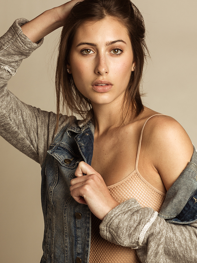 Model Haley Mick in denim jacket over sheer mesh bodysuit covers her breast photographed in studio by Joshua Pyles